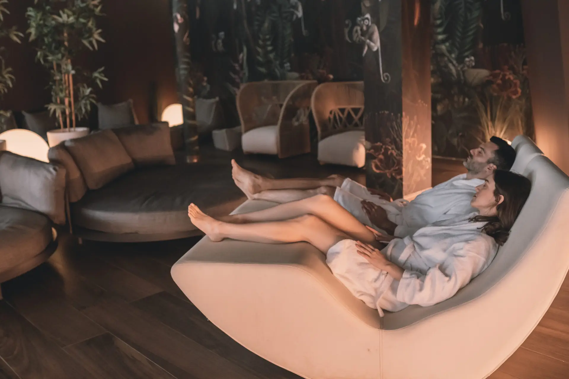 Una coppia si rilassa in accappatoi da spa su una moderna chaise longue dopo la riapertura della spa.