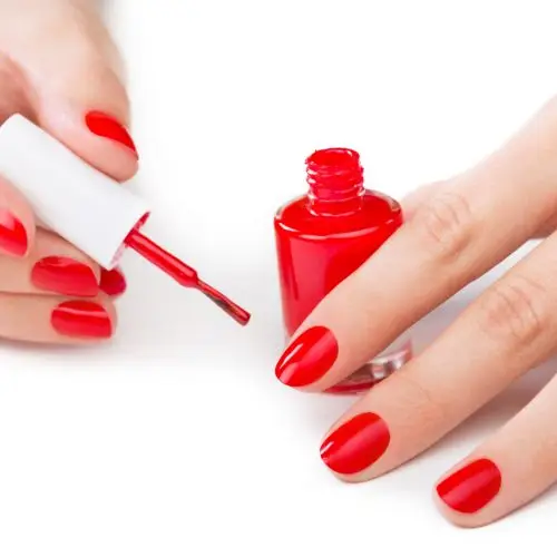 Woman applying red nail varnish on nails