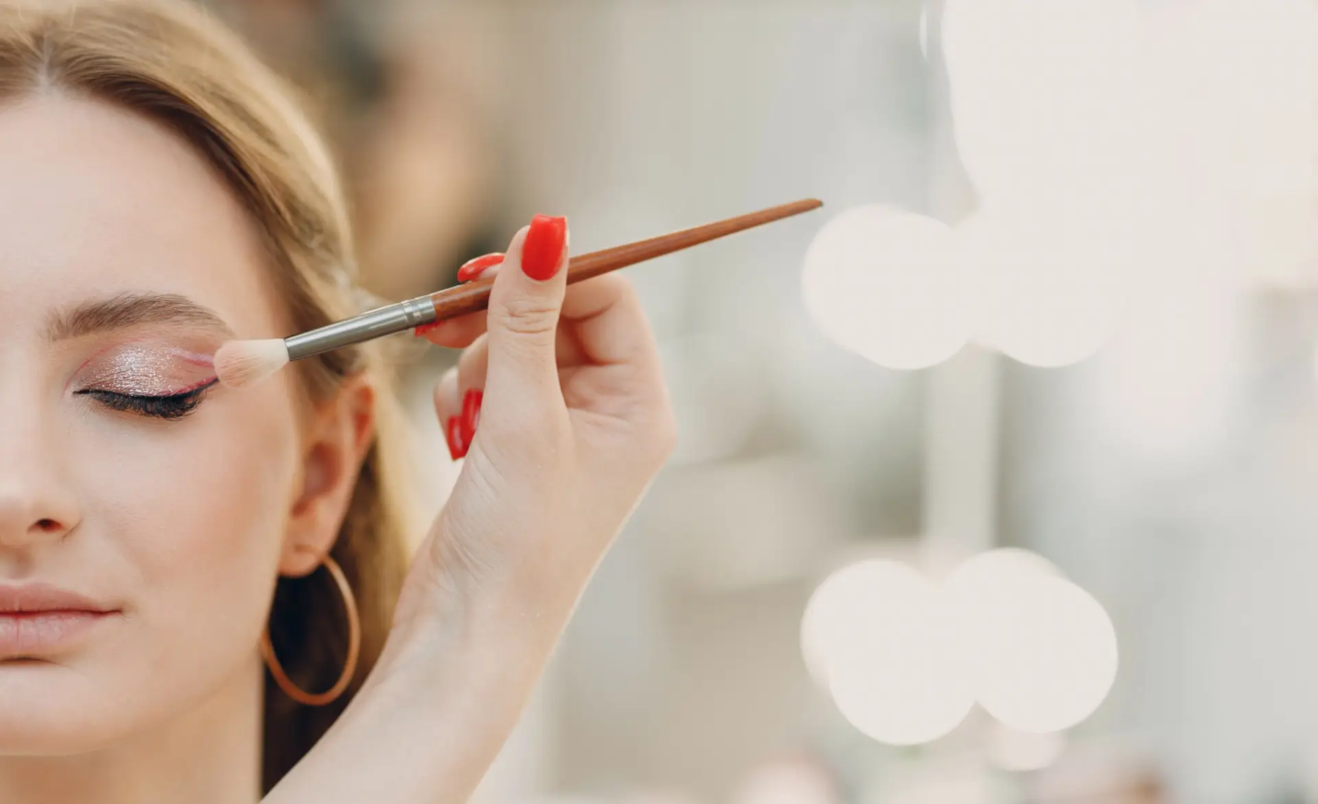 Primo piano del truccatore che applica l'ombretto sull'occhio di una cliente durante una riapertura.