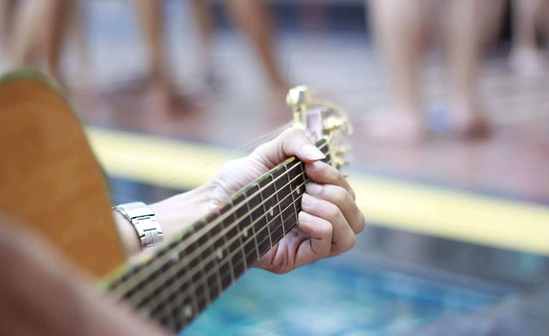 Primo piano delle mani di una persona che suona una chitarra acustica durante un evento di riapertura.