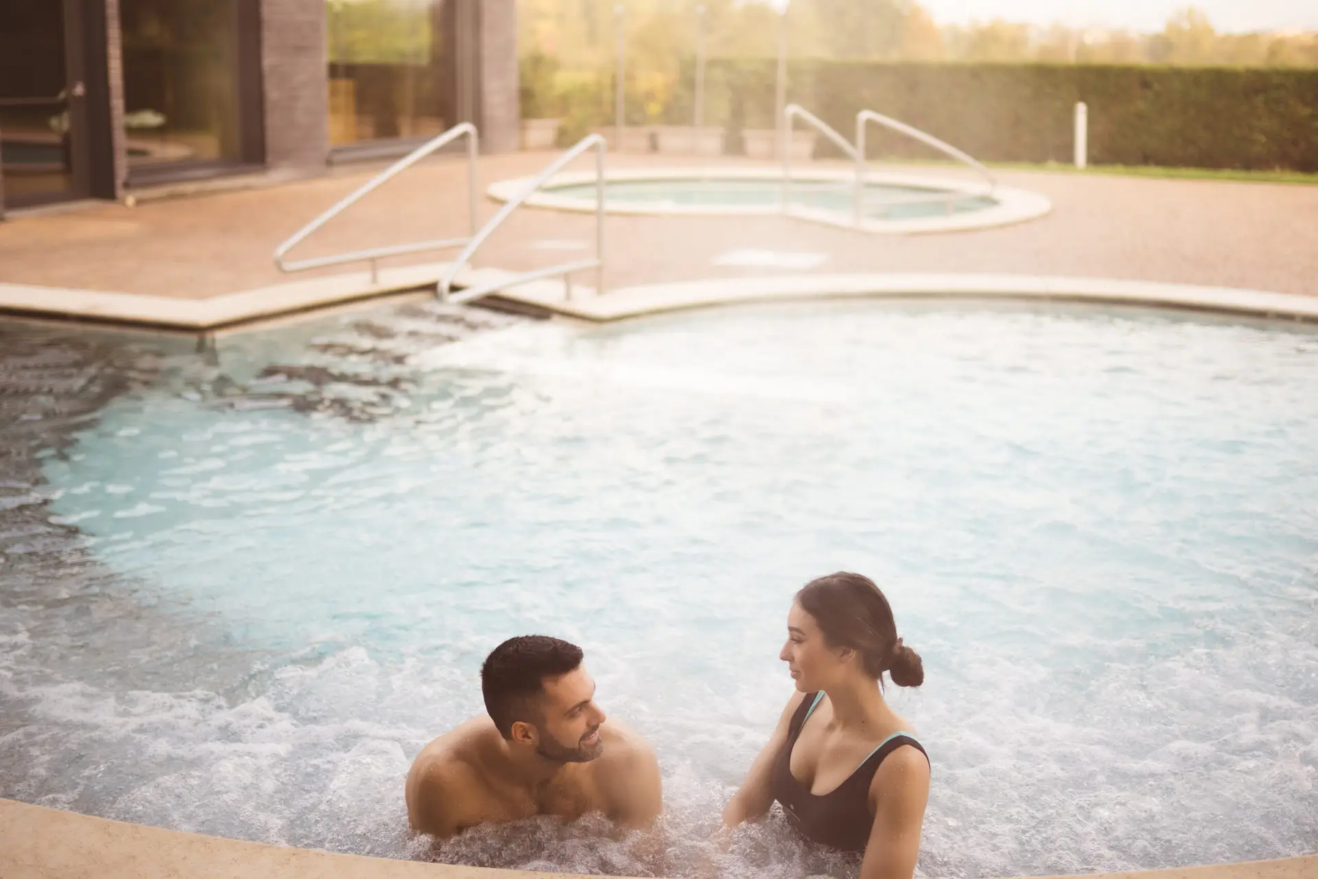 Coppia che si rilassa nella vasca idromassaggio di una spa, godendosi un Percorso Benessere.