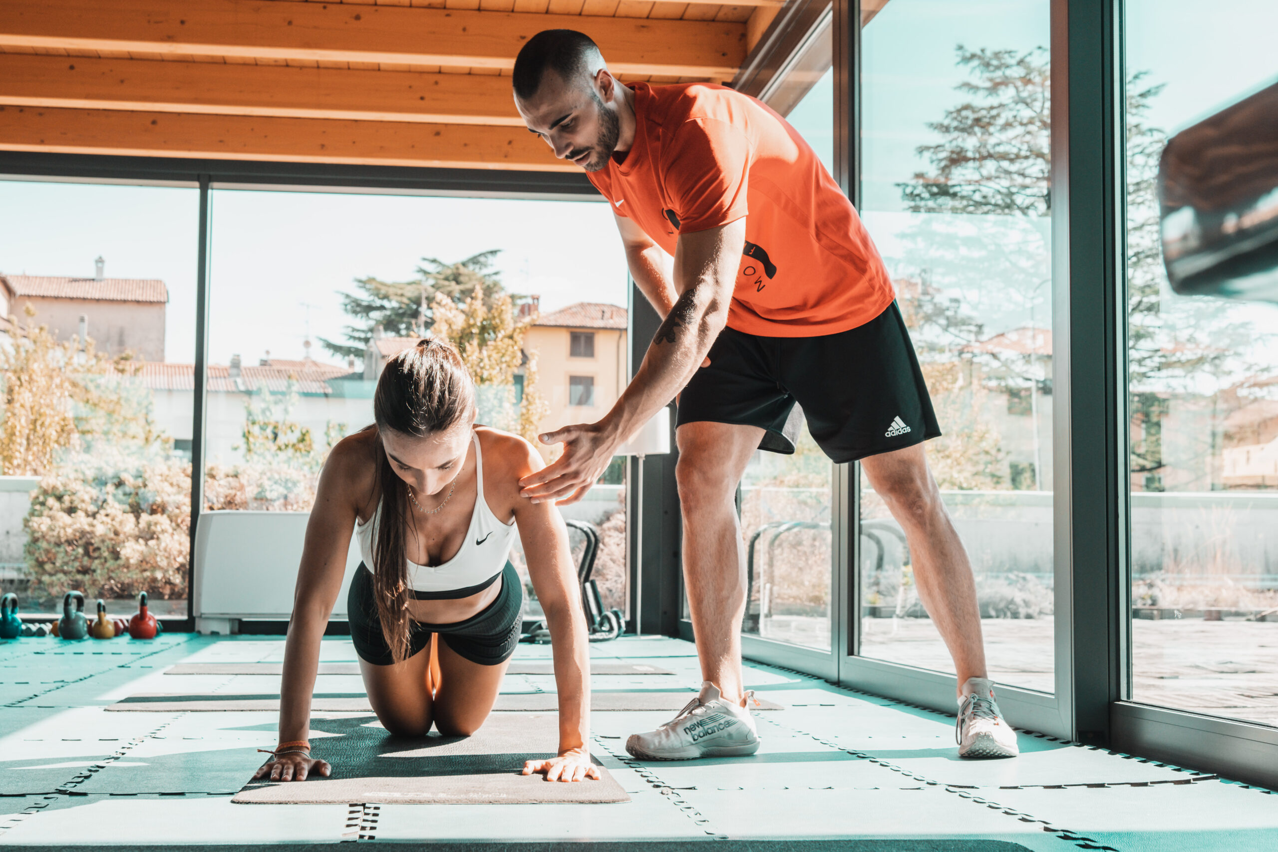Personal trainer che aiuta una donna con l'esercizio di plank