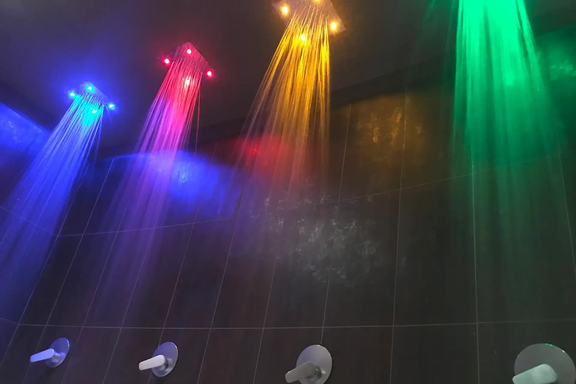 Soffioni doccia LED multicolori in una spa di lusso, per un'esperienza di cromoterapia all'insegna del benessere.