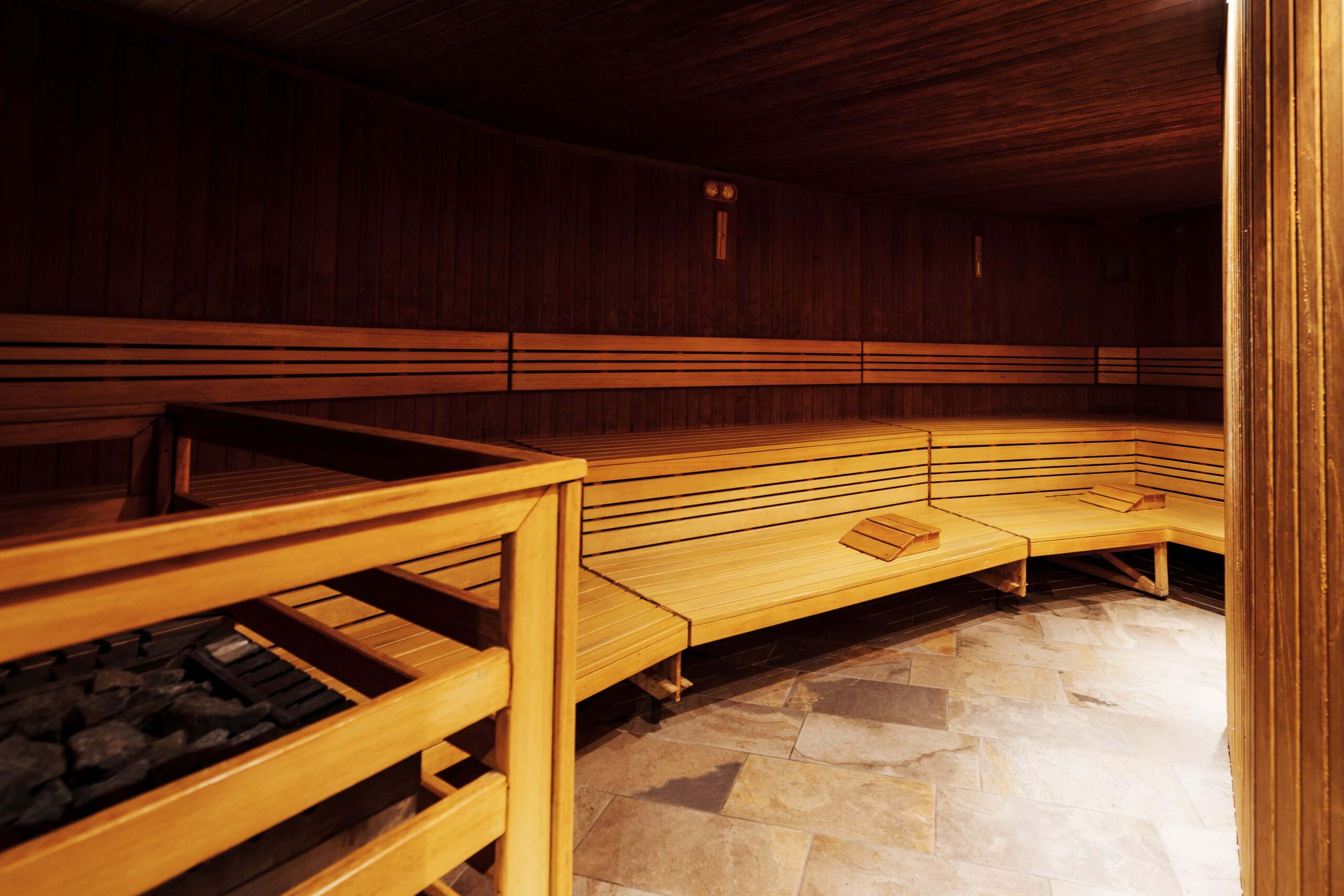 Interno di sauna in legno con panche e pietre. Percorso Benessere.