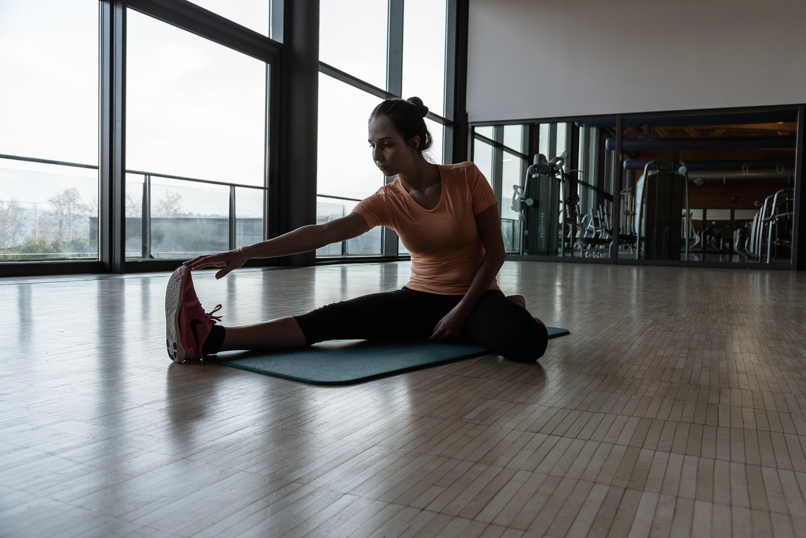 Donna che si allunga su un tappetino da yoga in palestra. Fitness.