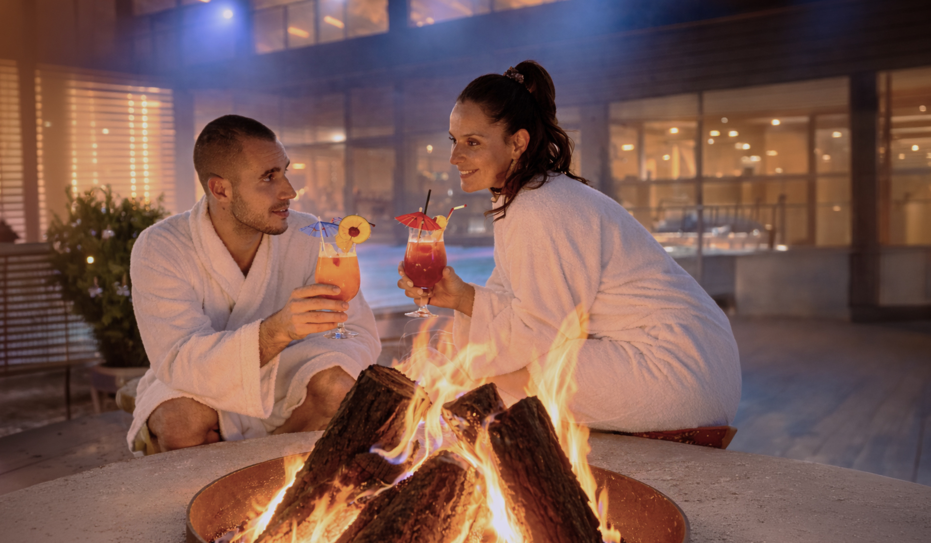 Coppia in accappatoio con cocktail davanti al fuoco. Grill&Chill Night a Monticello SPA.