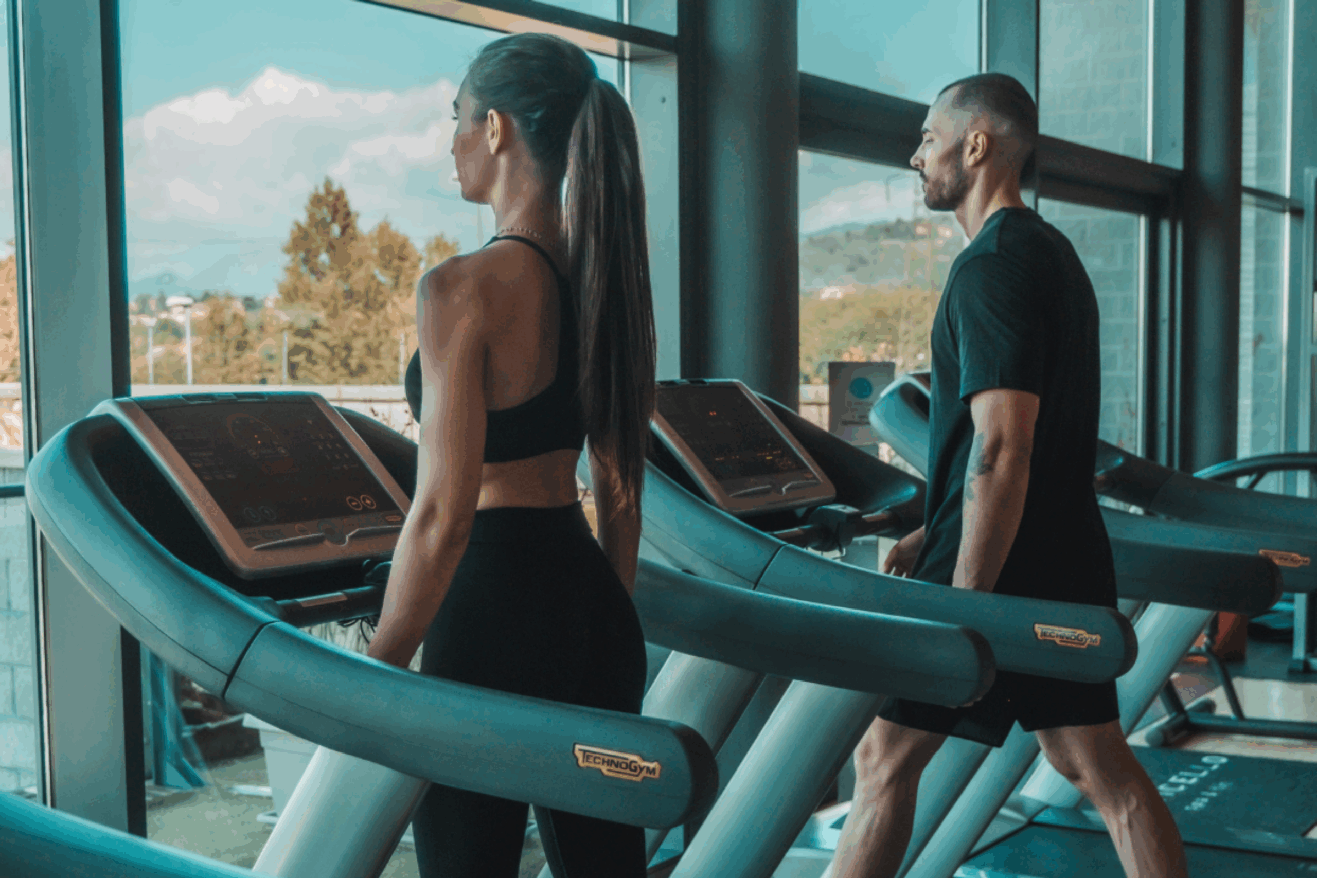 Uomo e donna si allenano sui tapis roulant in palestra